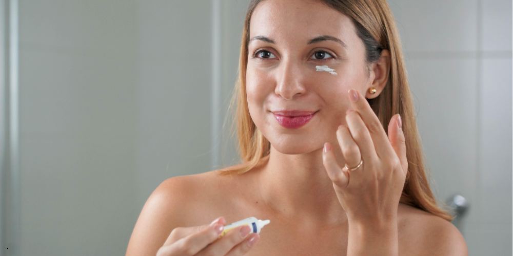a woman is applying eye cream